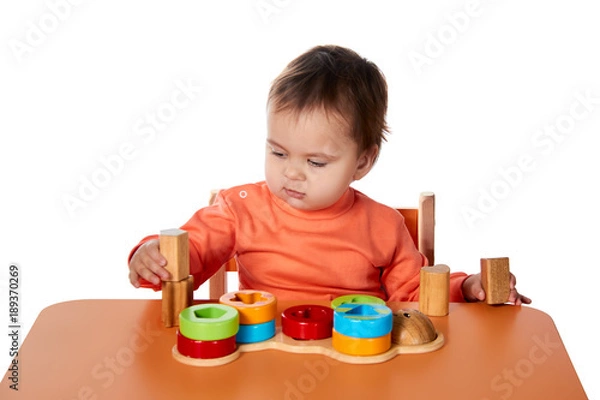 Fototapeta Child little girl learning to use colorful logic game isolated on white background