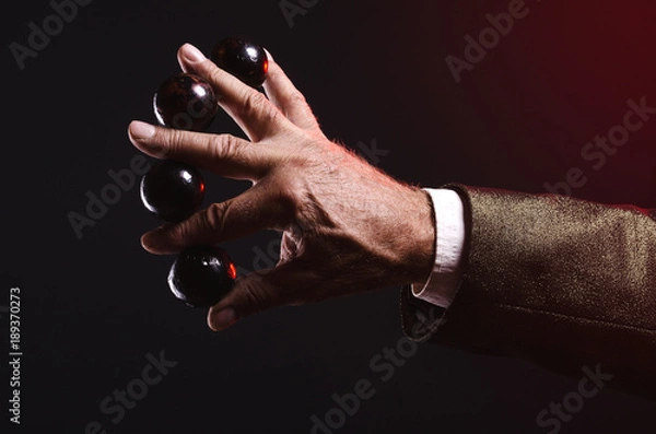 Fototapeta Magician shows trick with magic balls. Manipulation with props. Sleight of hand.