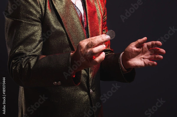 Fototapeta Magician shows trick with a coin. Manipulation with props. Sleight of hand.