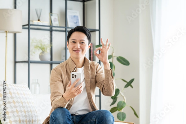 Obraz リビングでスマホを使うミドルの男性