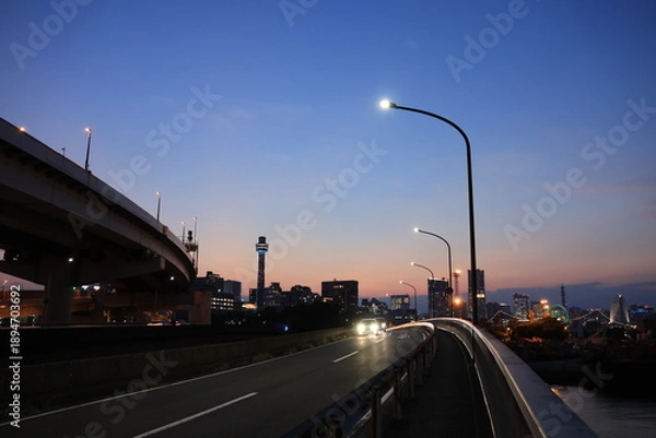 Obraz 日没直後　オレンジ色に染まる空と横浜の新山下付近の車道とみなとみらいのシルエットと車道