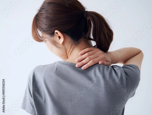 Obraz 首と肩のこりに悩み痛みを感じて後ろから首を押さえる女性の後ろ姿