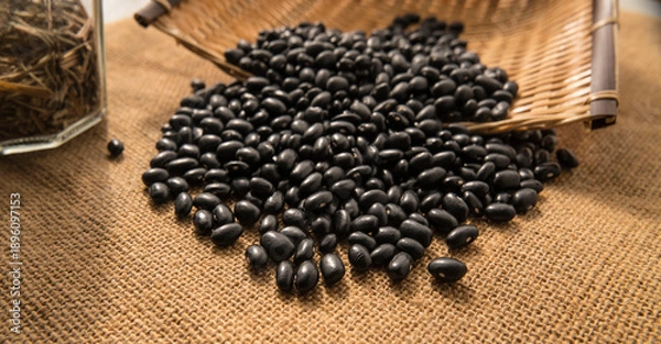 Obraz Background image. Black beans scattered in a straw container.