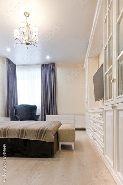 Obraz Спальня в светлых тонах с темной кроватью и синими шторами