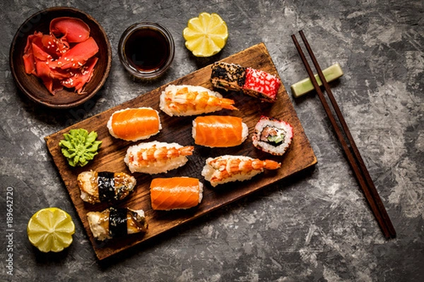 Fototapeta sushi and sushi rolls, sushi nigiri on stone plate on dark background, mustard wasabi, and ginger