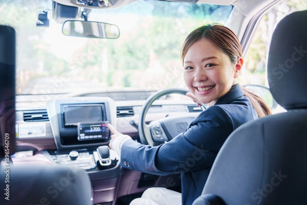 Obraz 笑顔で料金の案内をするタクシードライバーの女性