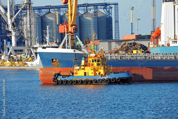 Fototapeta Tugboat assisting bulk cargo ship