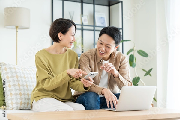 Obraz リビングでスマホとパソコンを使うミドルの夫婦