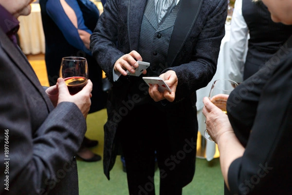 Obraz The magician shows a card trick for two spectators.