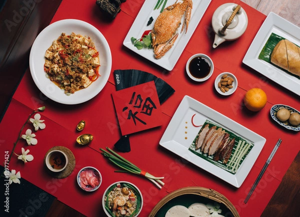 Fototapeta Concept picture for Chinese new year table set up and traditional Chinese dishes on red background with Chinese word means fortune.