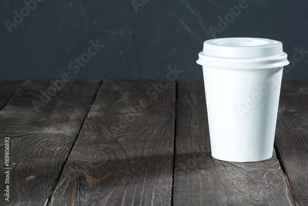 Fototapeta white paper cup/ Background of a wooden countertop with a white paper cup for coffee to go