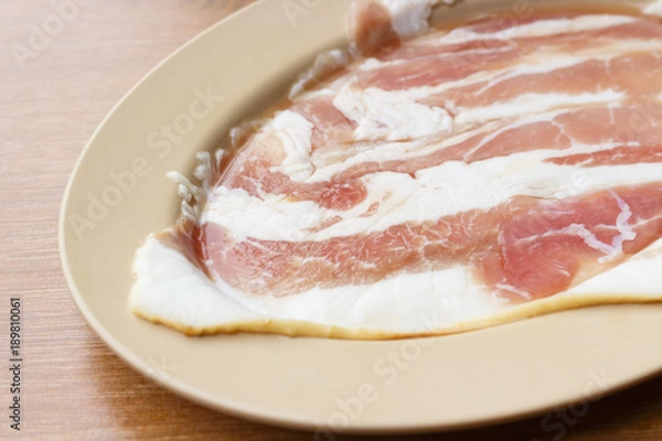 Fototapeta Sliced raw bacon on plate