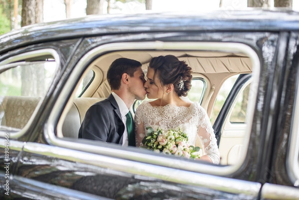 Fototapeta wedding couple kissing and hugging in old vintage retro car