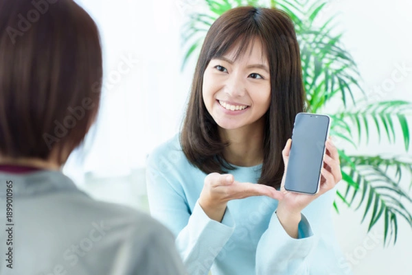 Obraz スマートフォンの画面を見せる女性
