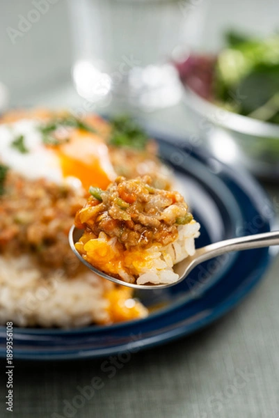 Obraz スプーンで掬い半熟卵をのせたキーマカレーを食卓でたべる