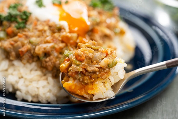 Obraz 食卓でスプーンを使い半熟卵をのせたキーマカレーをたべる