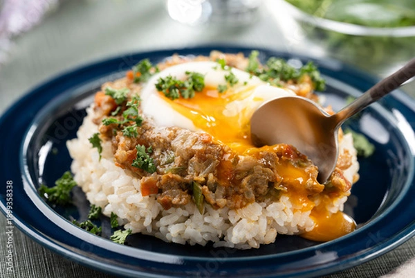 Obraz 食卓で半熟卵が絡むキーマカレーをスプーンで掬ってたべる