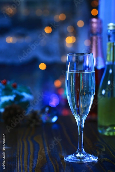 Fototapeta A glass of Sparkling wine in front of defocused colorful lights of blue tone background, cool tone and romantic mood 1