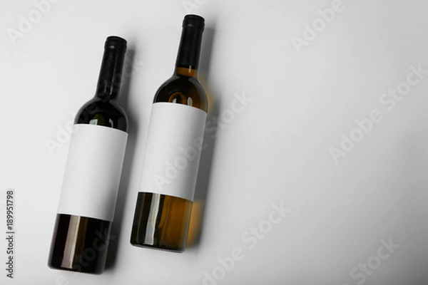 Fototapeta Wine bottles with blank labels on light background. Mock up for design