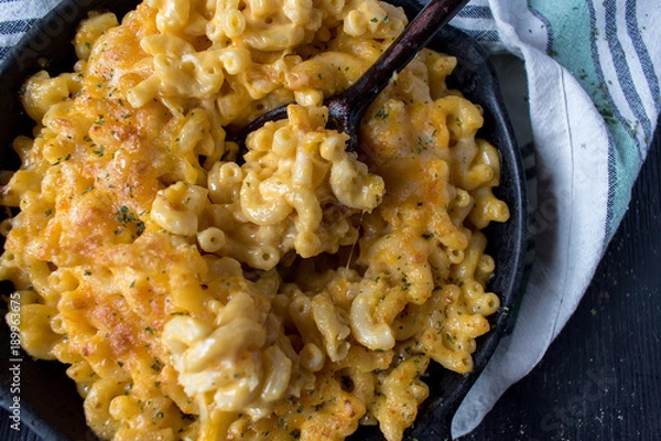 Fototapeta gourmet baked macaroni and cheese noodles in rustic cast iron dish top view
