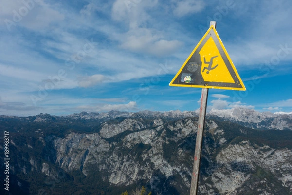 Obraz Warning sign for falling off a cliff or mountain. There are mountains in the background indicating the danger.