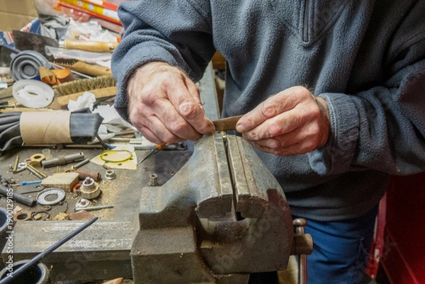 Obraz A person shapes metal using tools in a workshop