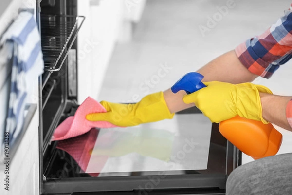 Obraz Man cleaning oven in kitchen, closeup