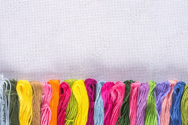 Fototapeta Colored thread for embroidery on white canvas. Copy spase.