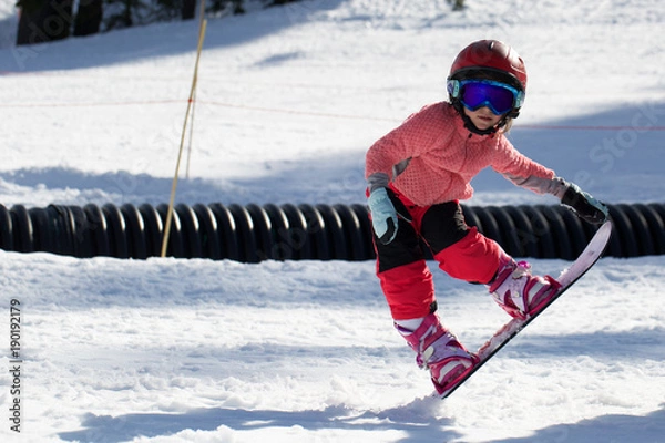 Obraz Little Cute Girl Snowboarding  making a tricks at ski resort in sunny winter day. Caucasus Mountains. Mount Hood Meadows Oregon 
