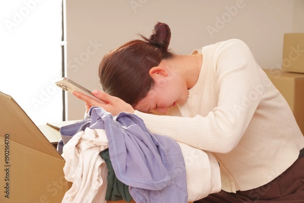 Obraz スマホを使いながら断捨離をする女性