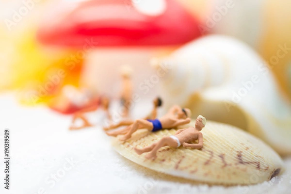 Fototapeta Miniature people : Group travelers sunbathing on shells at the beach . Image use for business travel concept.