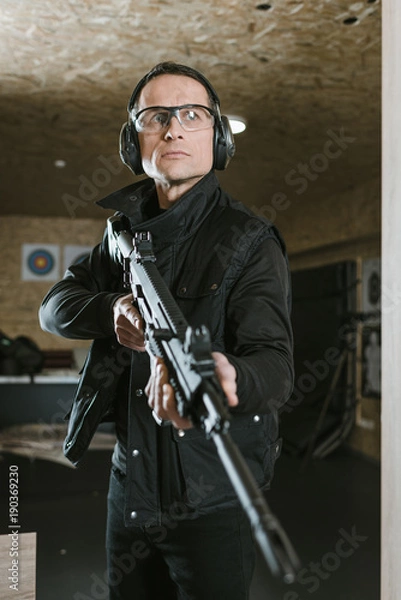 Obraz handsome man with rifle in shooting range