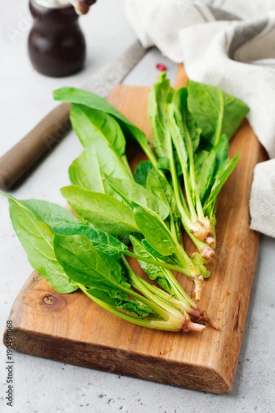 Fototapeta Fresh raw spinach leaves on a wooden rustic stand on a gray old concrete background. Ingredients for salad. Selective focus. Top view. Copy space.