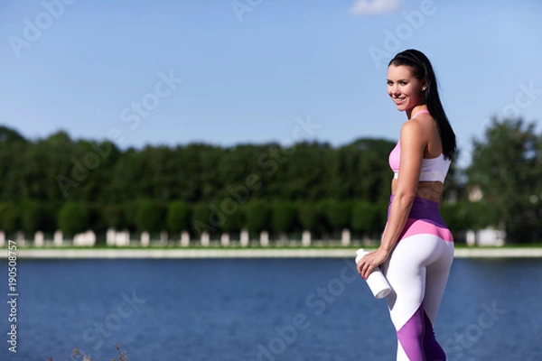Obraz The woman athlete is near water and smiles.