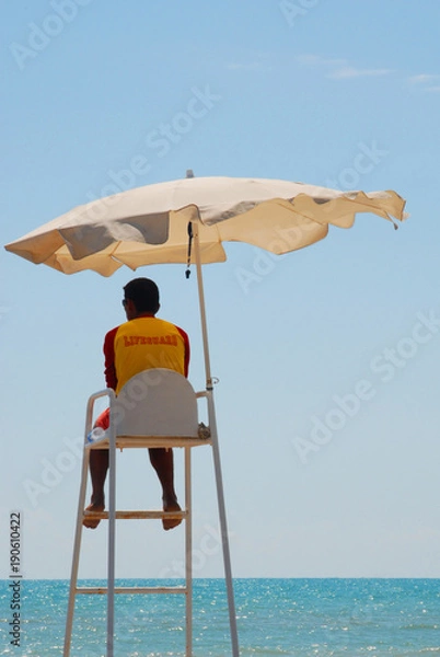 Fototapeta Lifeguard on duty in a toursim resort in the Mediterranean and blue sky and sea in the background