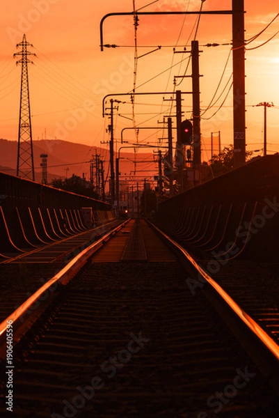 Obraz 夕焼けに染まる線路と架線柱のシルエット　鉄道インフラの情景