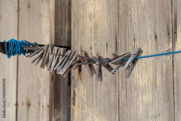 Obraz 古い板の壁の家に吊るされたたくさんの古い洗濯バサミ