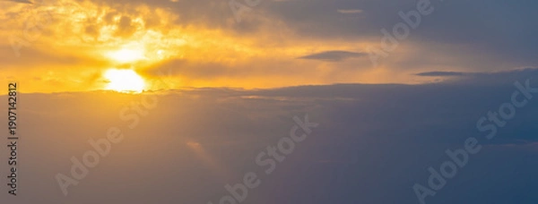 Obraz Cloudy Sunset Sky with Yellow Sun among Gray Clouds