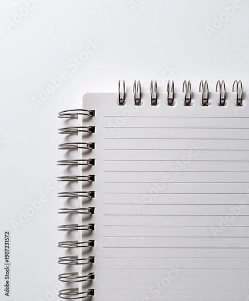 Obraz A spiraled, lined notebook lies partially open against a white backdrop