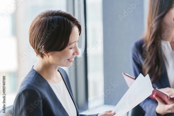 Fototapeta 紙資料を持って会議するビジネスパーソン