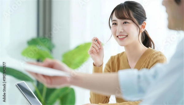 Obraz 対面の相手から書類を受け取り笑顔を見せる女性社員