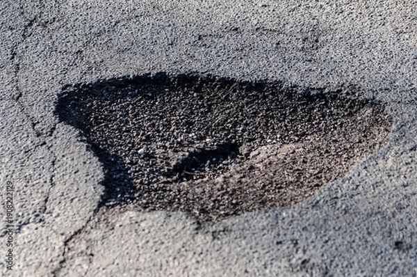 Fototapeta ein Schlagloch in einer Straße nach dem Winter