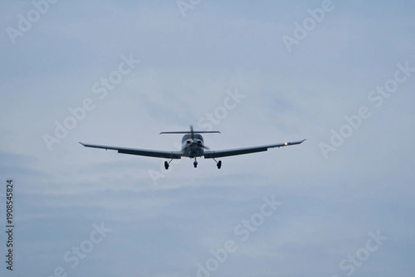 Obraz Single-engine plane approaching the airport under a cloudy sky