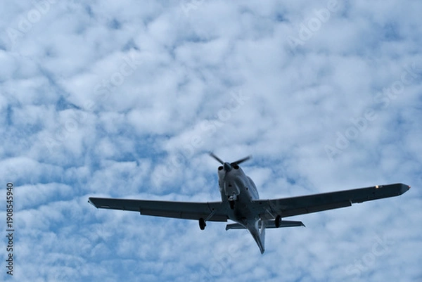 Obraz Single-engine plane approaching the airport under a cloudy sky