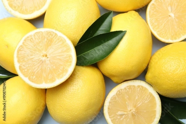 Obraz Ripe lemons and leaves on light background, flat lay