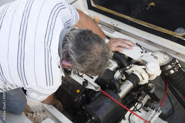 Fototapeta close-up of a man repairing a boat engine