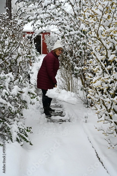 Obraz Eine Frau schiebt Schnee