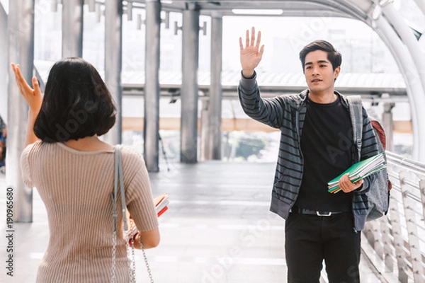 Fototapeta Happy students waving and saying hello with friend