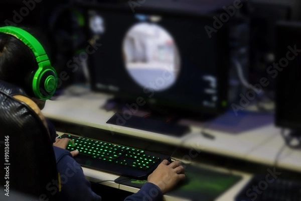 Fototapeta Stressed gamer while playing computer games until morning at internet cafe, game addiction concept, gamer lifestyle