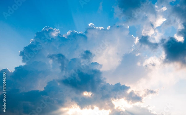 Fototapeta Dramatic clouds with sun rays breaking through blue sky
